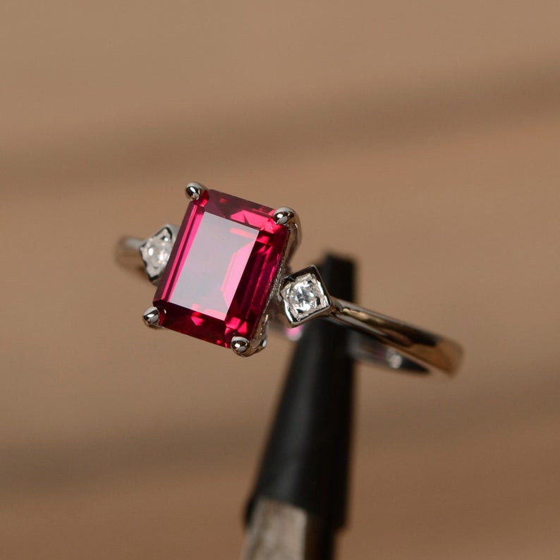 1.75 Ct Emerald Cut Red Ruby & White Round CZ Three-Stone Ring In 925 Sterling Silver
